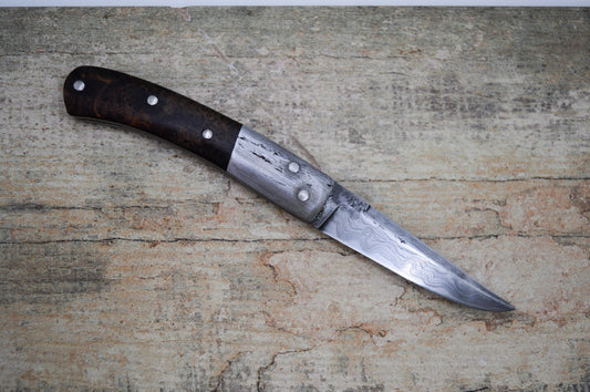 Hand-forged slipjoint folding knife with a pattern-welded blade. Wrought Iron Bolsters with Black Ash Burl Scales. Non-locking UK Legal Carry