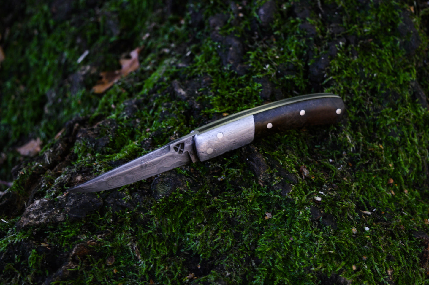 Hand-forged slipjoint folding knife with a pattern-welded blade. Wrought Iron Bolsters with Black Ash Burl Scales. Non-locking UK Legal Carry